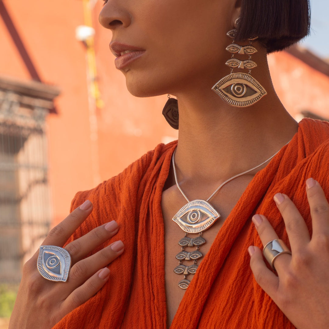 Woman wearing a large sterling silver lucky eye pendant, earrings, and ring, designed in a vibrant boho aesthetic.