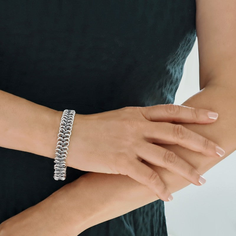 A woman in a green dress wearing a two-tone sterling silver double row chain link bracelet.