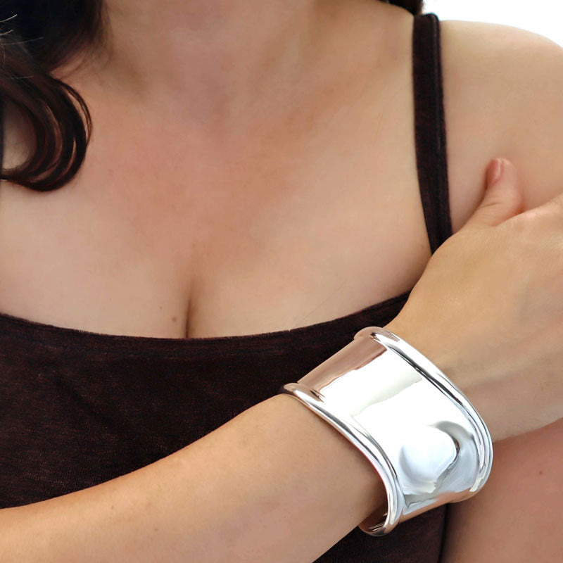 Woman with black top wearing a large UK hallmarked sterling 925 silver handmade cuff style bracelet