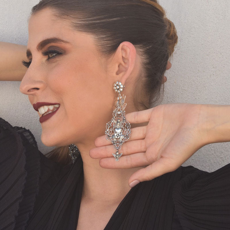 Woman wearing a long Mexican sterling 925 silver Frida Kahlo inspired chandelier earring.