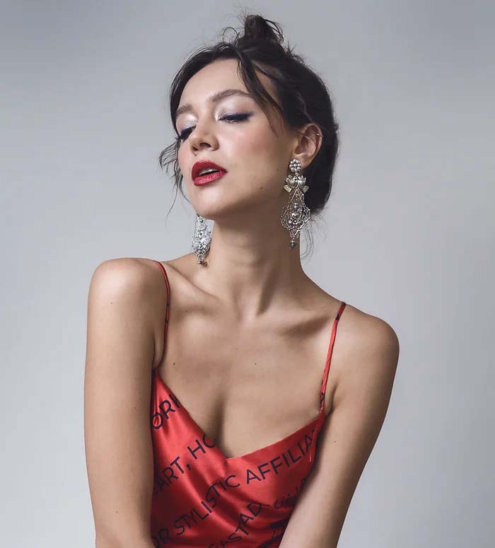 Large Frida Kahlo style lovebird and flowers sterling silver chandelier earrings worn by a woman in a red silk top