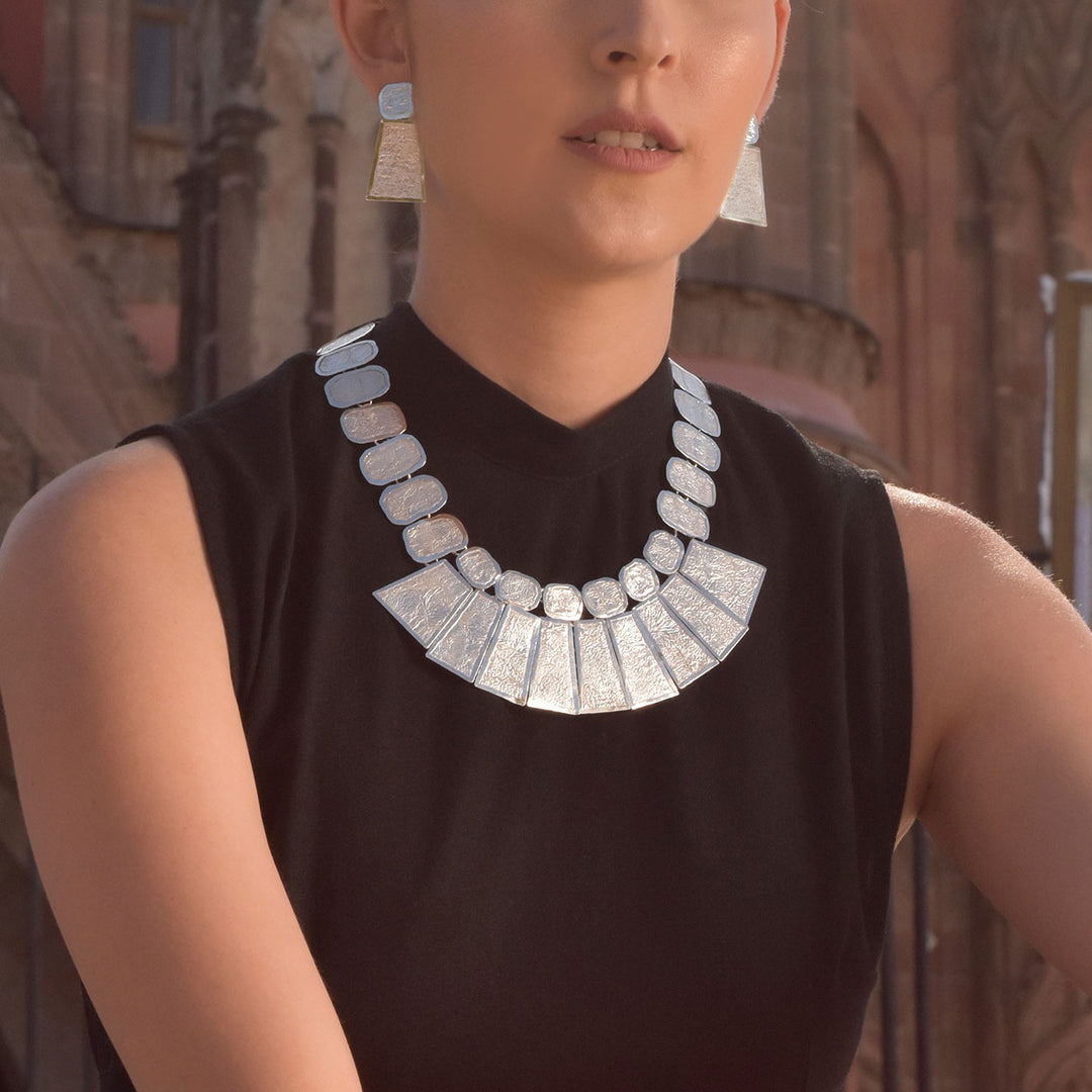 Large statement sterling 925 silver bib necklace and matching earrings worn by a woman in a back top