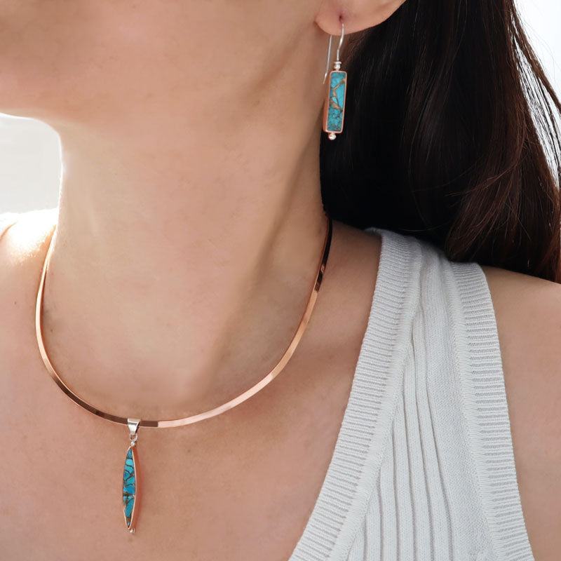 Woman wearing a polished copper choker necklace with a turquoise and copper pendant and matching earrings
