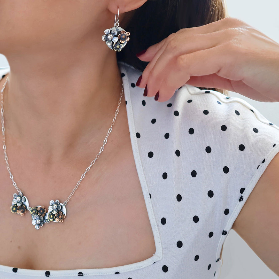 Two tone 925 sterling silver and flower necklace with matching earrings worn by a woman in a black and white polka dot blouse