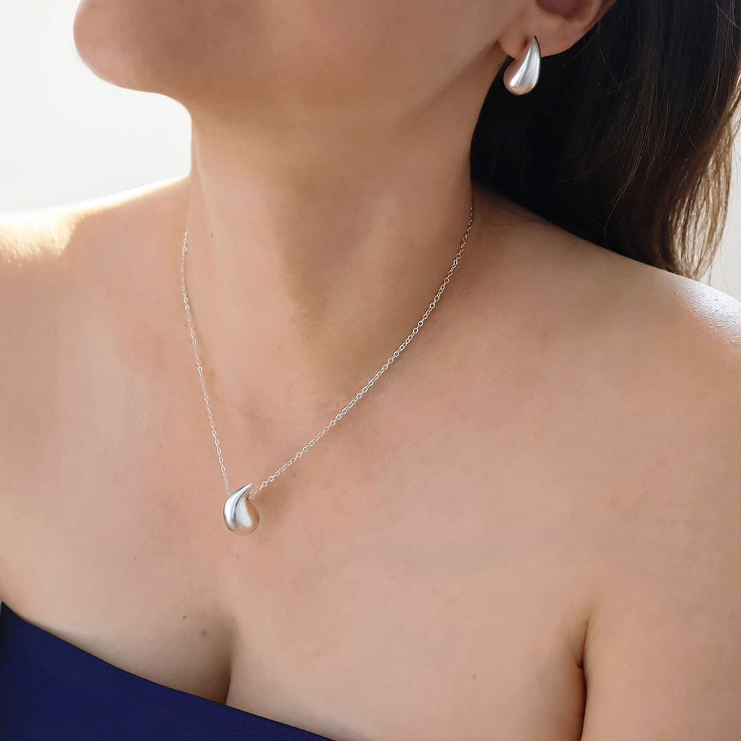 Teardrop pendant and chain necklace and matching earrings worn by a woman with dark hair 