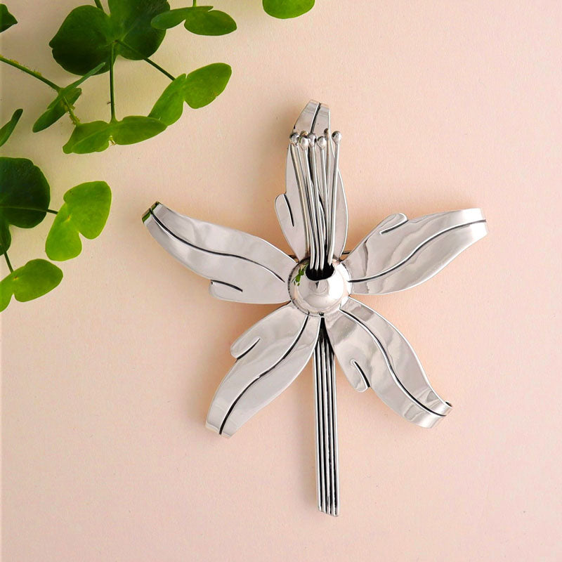 A large 925 sterling silver pendant for women in the shape of an orchid flower on a pale background.