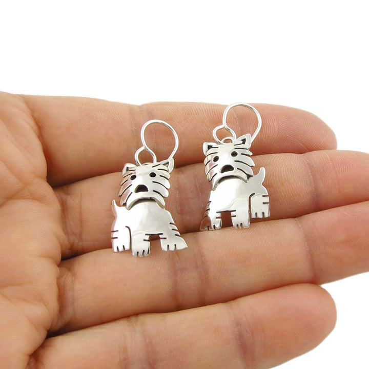 Sterling 925 Silver handmade terrier dog dangling earrings for women held between fingers on a white background