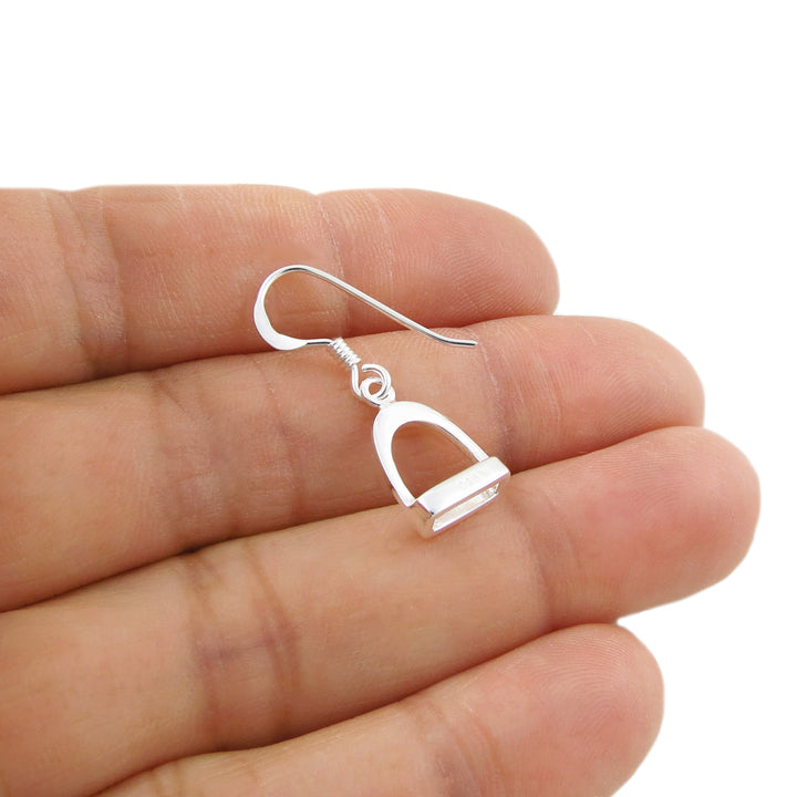 Sterling 925 silver equestrian horse stirrup earring on a hand to show scale.