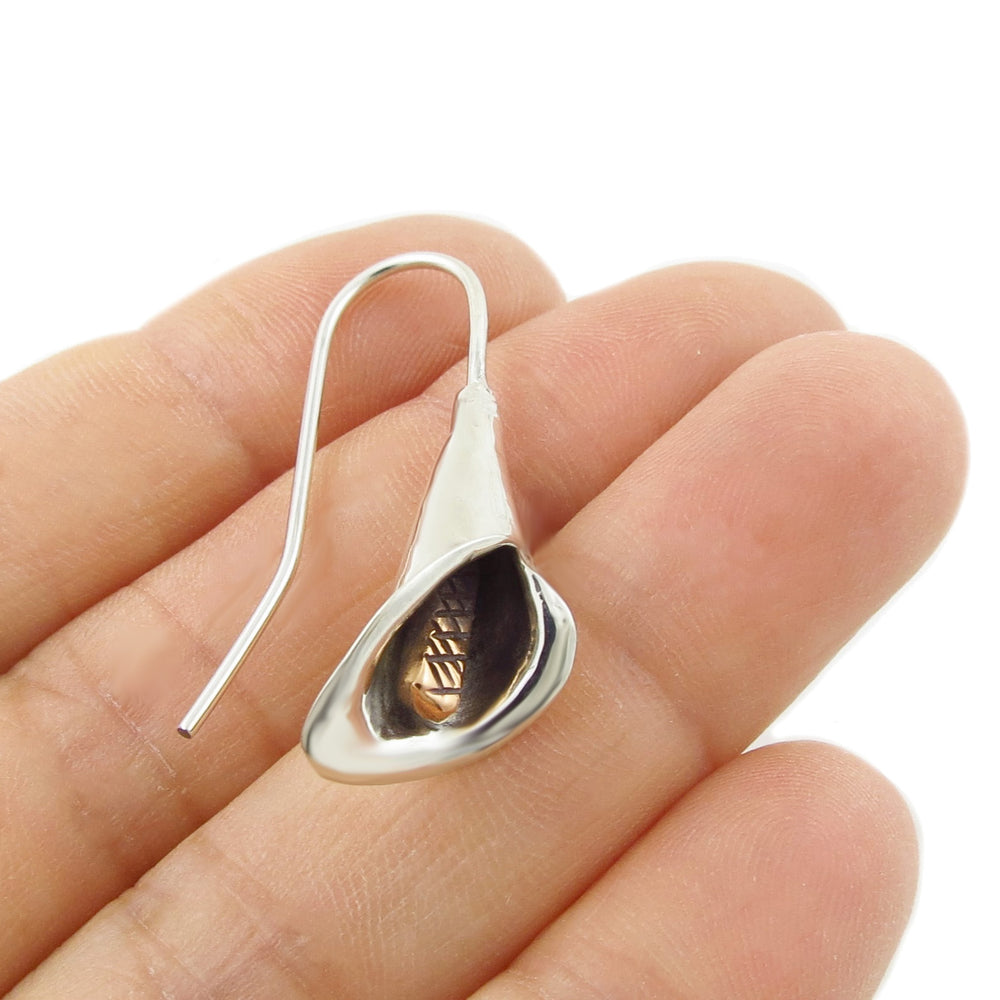 Mixed metals 925 Silver and copper calla lily flower earring held between fingers on a white background