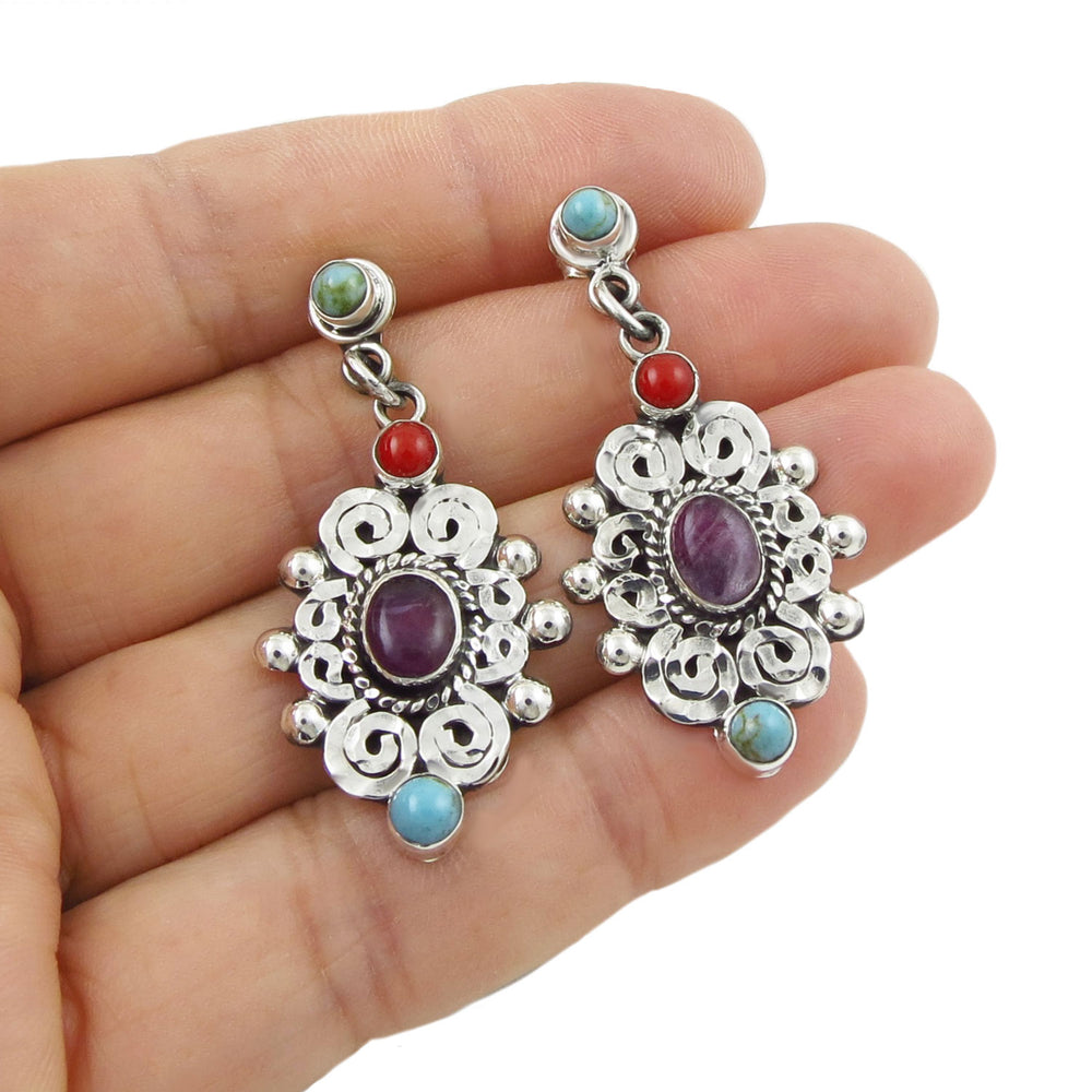 Long 925 Silver earrings with gemstones held in a woman's hand on a white background
