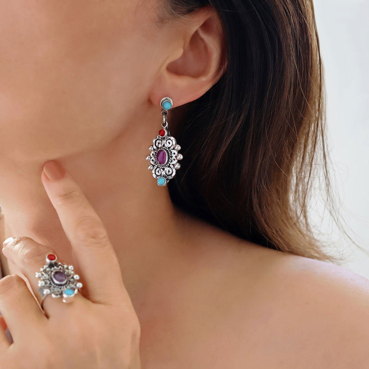 A woman wearing sterling 925 silver baroque drop earrings with multi-coloured gemstone inlays.