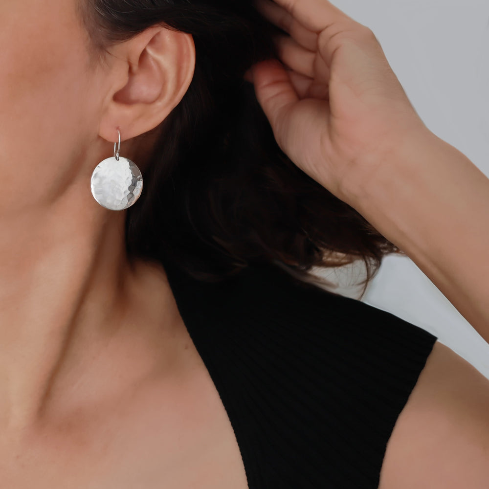 A woman wearing 925 Sterling Silver Hammered Drop Earrings with a curved circle design hanging on long ear hooks.