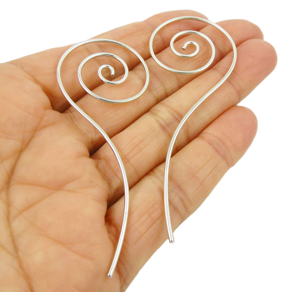 Long 925 sterling silver coiled spiral threader earrings held in a person's hand on a white background. 