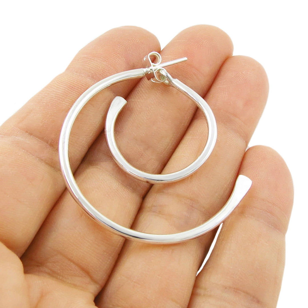 Sterling 925 Silver two part hoop earring held in a woman's hand against a white background