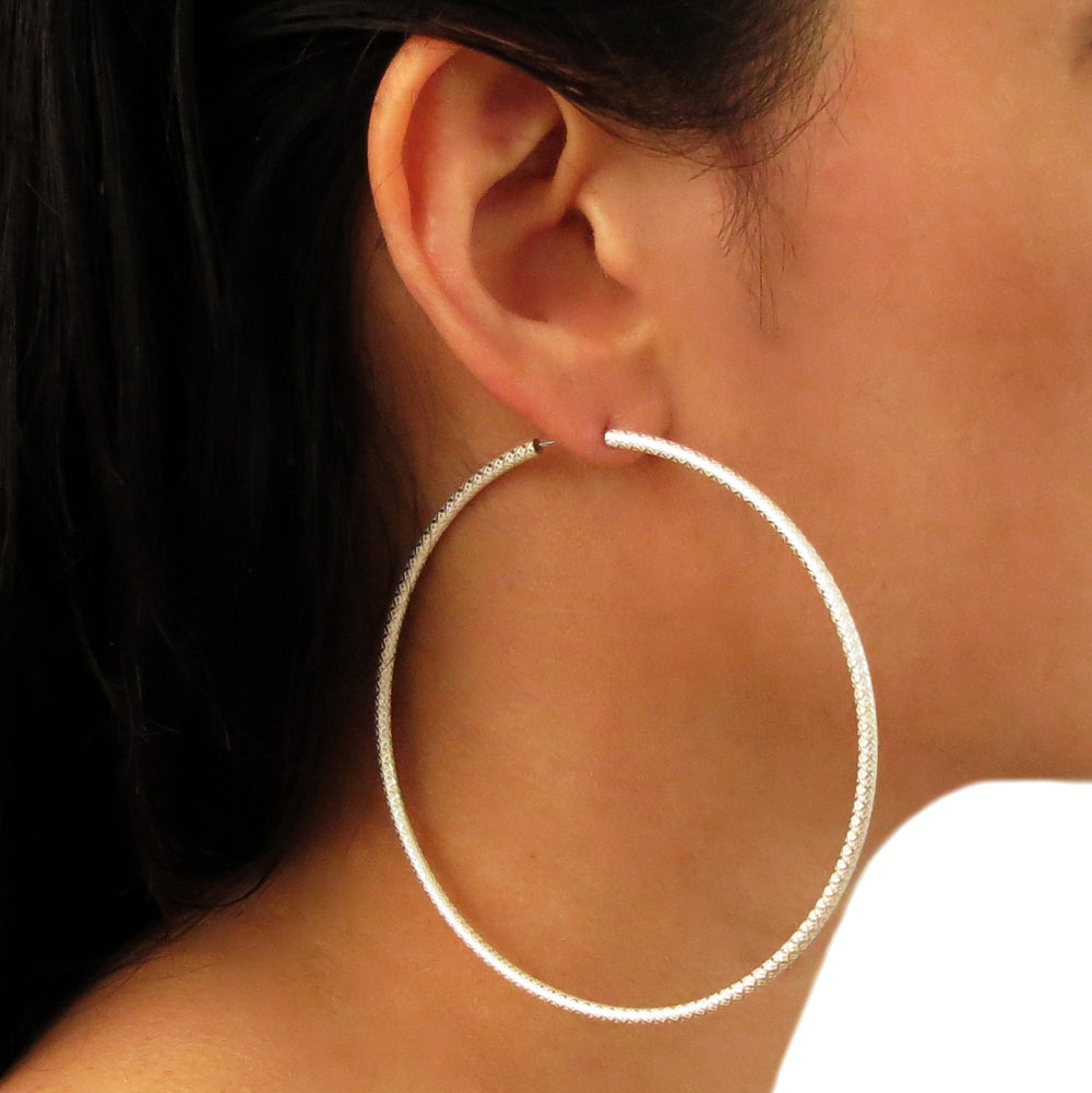 A close-up image of a woman's ear wearing a large 925 stelring silver gypsy hoop earring.