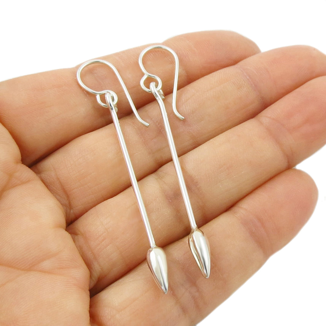 A pair of 925 silver drop earrings with long straight bars and teardrop-shaped ends, shown resting on an open hand against a white background.