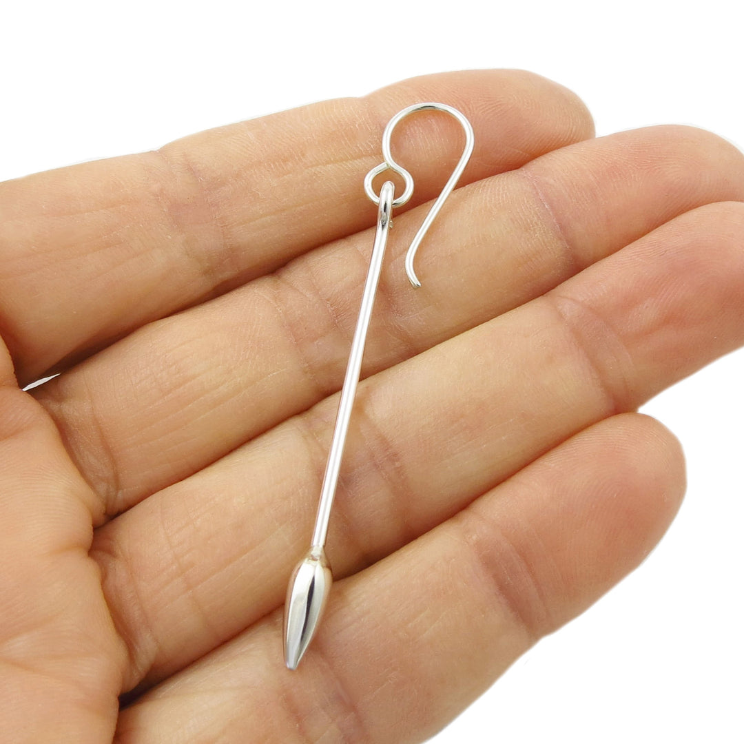 A sterling 925 silver drop earring with a curved hook and a long, tapered teardrop-shaped drop, shown resting on a person's hand against a white background.
