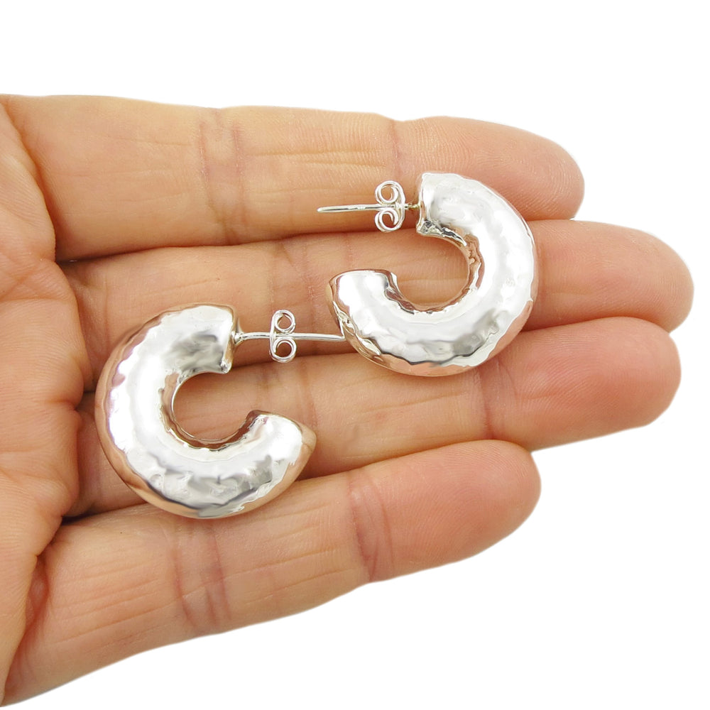 Chunky puffed circle hoop earrings held in a person's hand.
