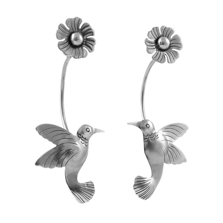 A pair of large Mexican 925 sterling silver hummingbird and flower earrings on a white background