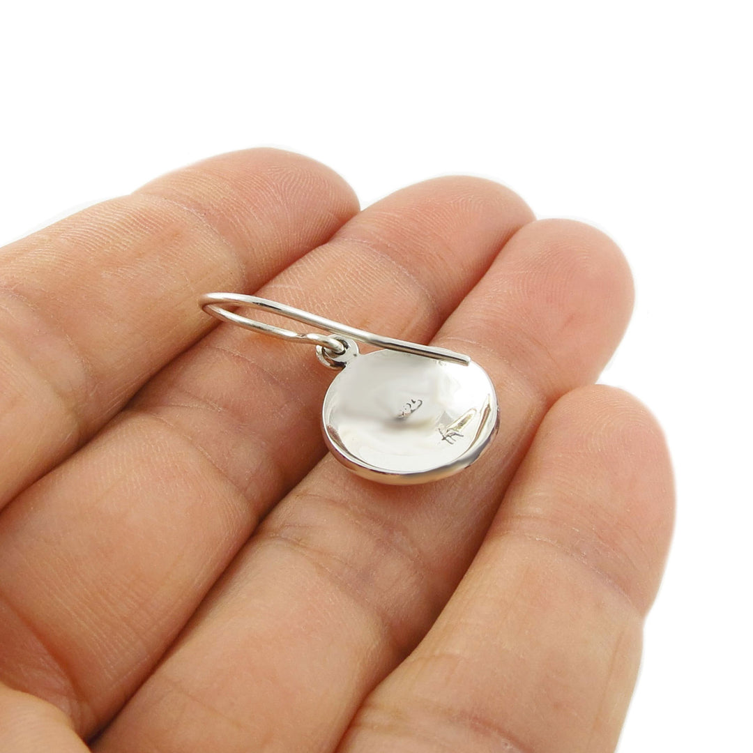 Reverse of a 925 silver earring  held in a hand to show the 925 hallmark against a white background