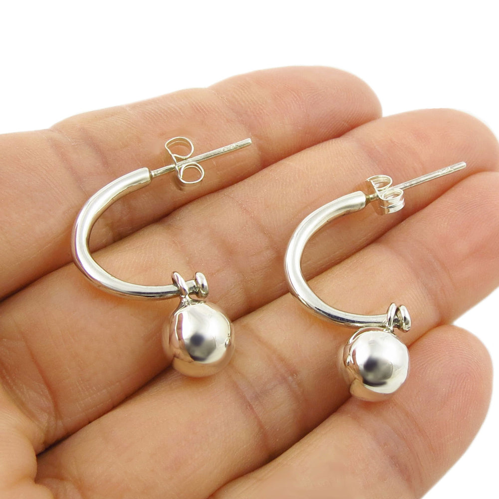 925 silver half hoop earrings with ball bead charms held in a hand on a white background