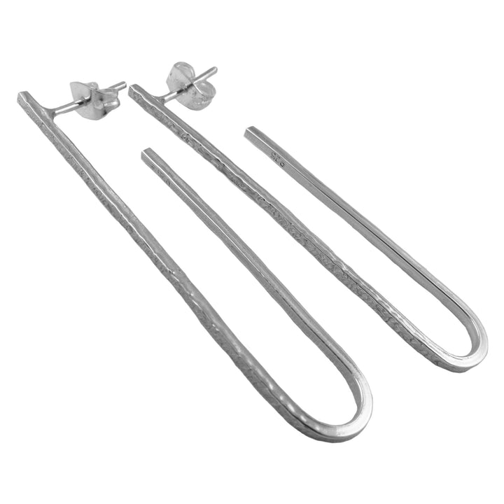 A unique pair of long 925 silver drop earrings handwrought from solid silver on a white background. 