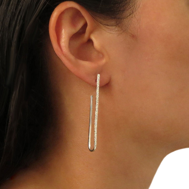 Long sterling 925 silver oval hoop earrings worn by a woman with dark hair