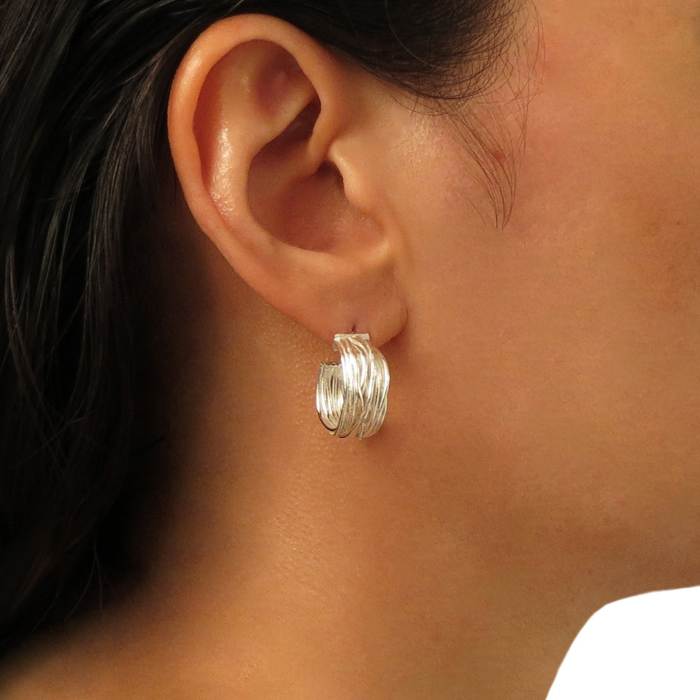 Woman with dark hair wearing a medium sized 925 sterling silver hoop earring with a wrapped wire design. 