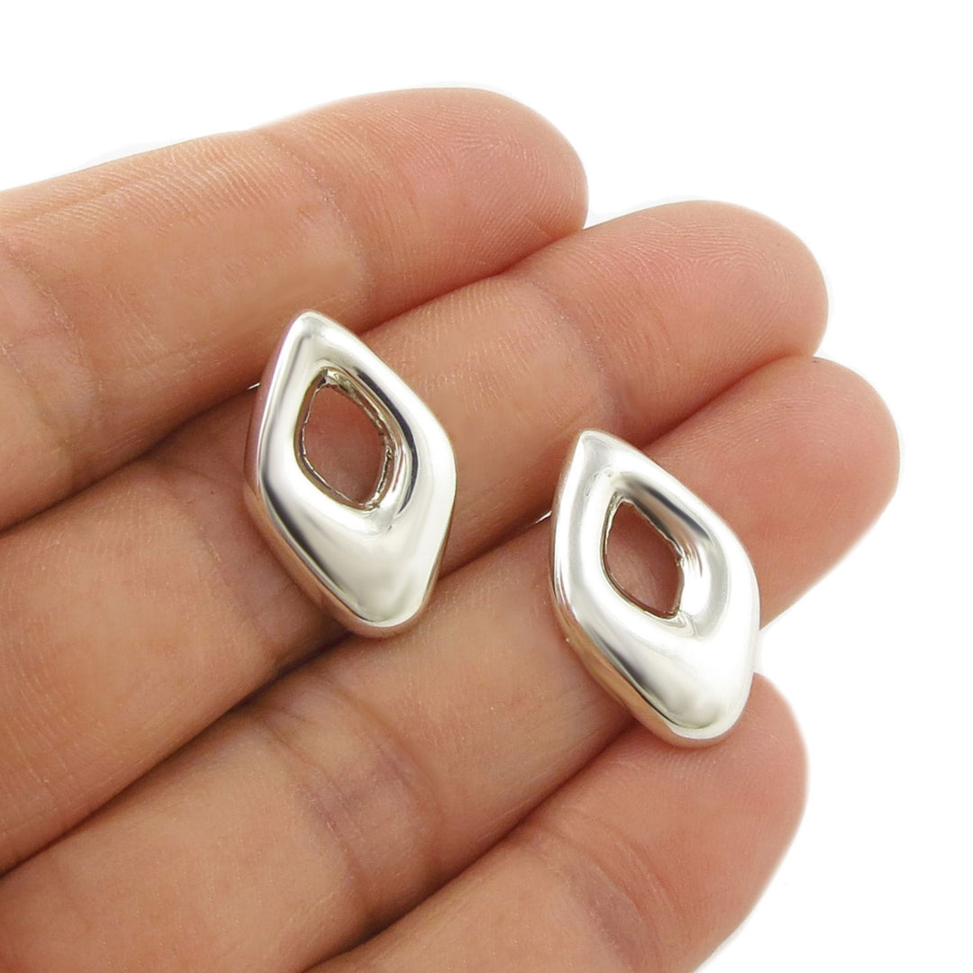Puffed rhombus shaped Mexican handmade 925 silver earrings for women held in a person's hand
