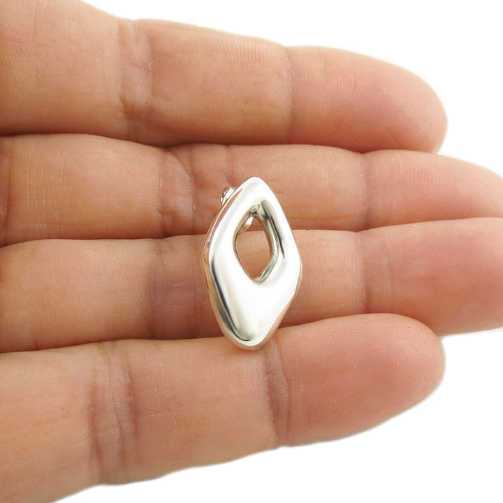 A large rhombus 925 sterling silver stud earring held in a woman's hand on a white background.  