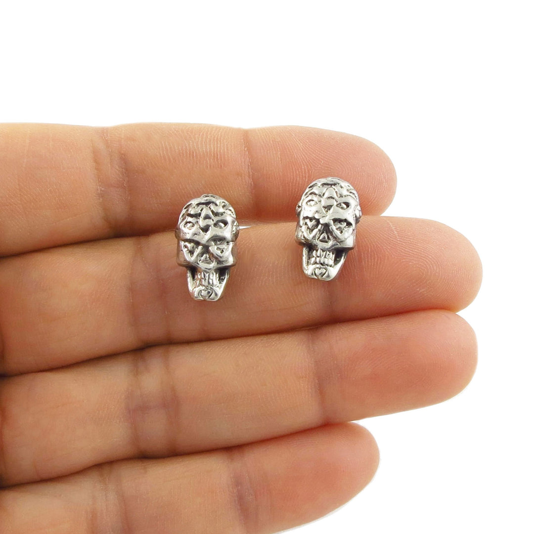 925 Silver dy fo the dead sugar skull earrings held between a woman's fingers on a white background