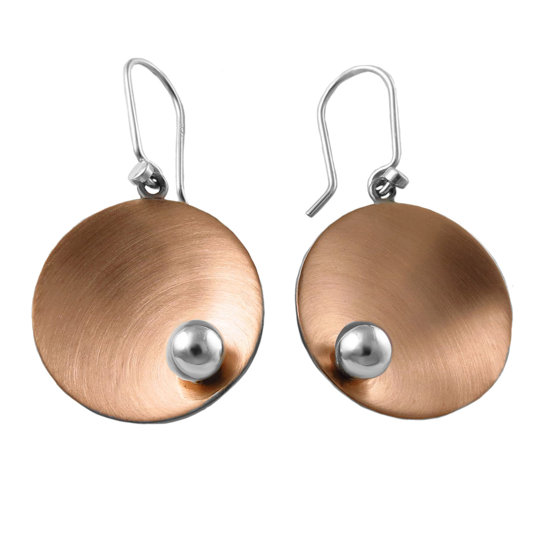 Pair of mixed metal copper disc earrings with silver accents on a white background