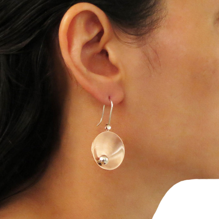 Close-up of a woman wearing a two tone copper and 925 silver earring with a silver ball bead accent in the center.