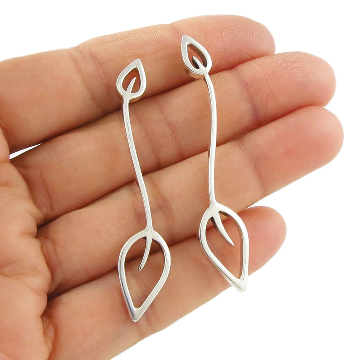 Sterling 925 Silver leaf-shaped drop earrings held between fingers on a white background