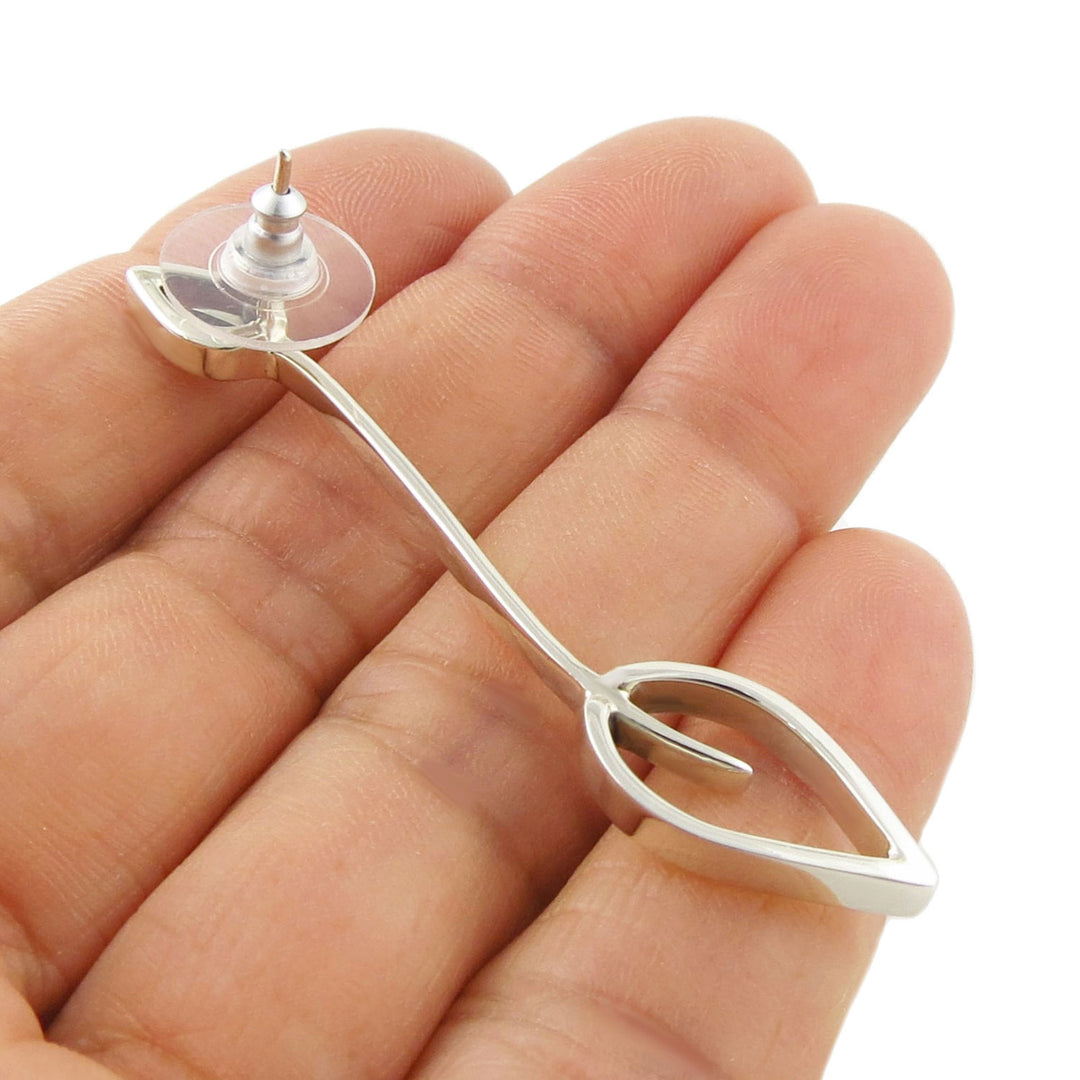 Sterling 925 Silver leaf shaped long drop earring held between a woman's fingers against a white background
