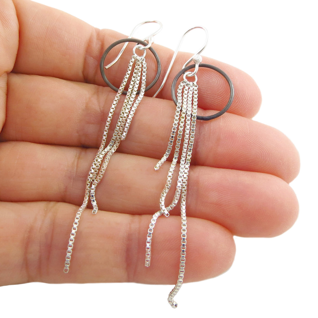 Mexican sterling silver long chain fringe earrings held between fingers on a white background