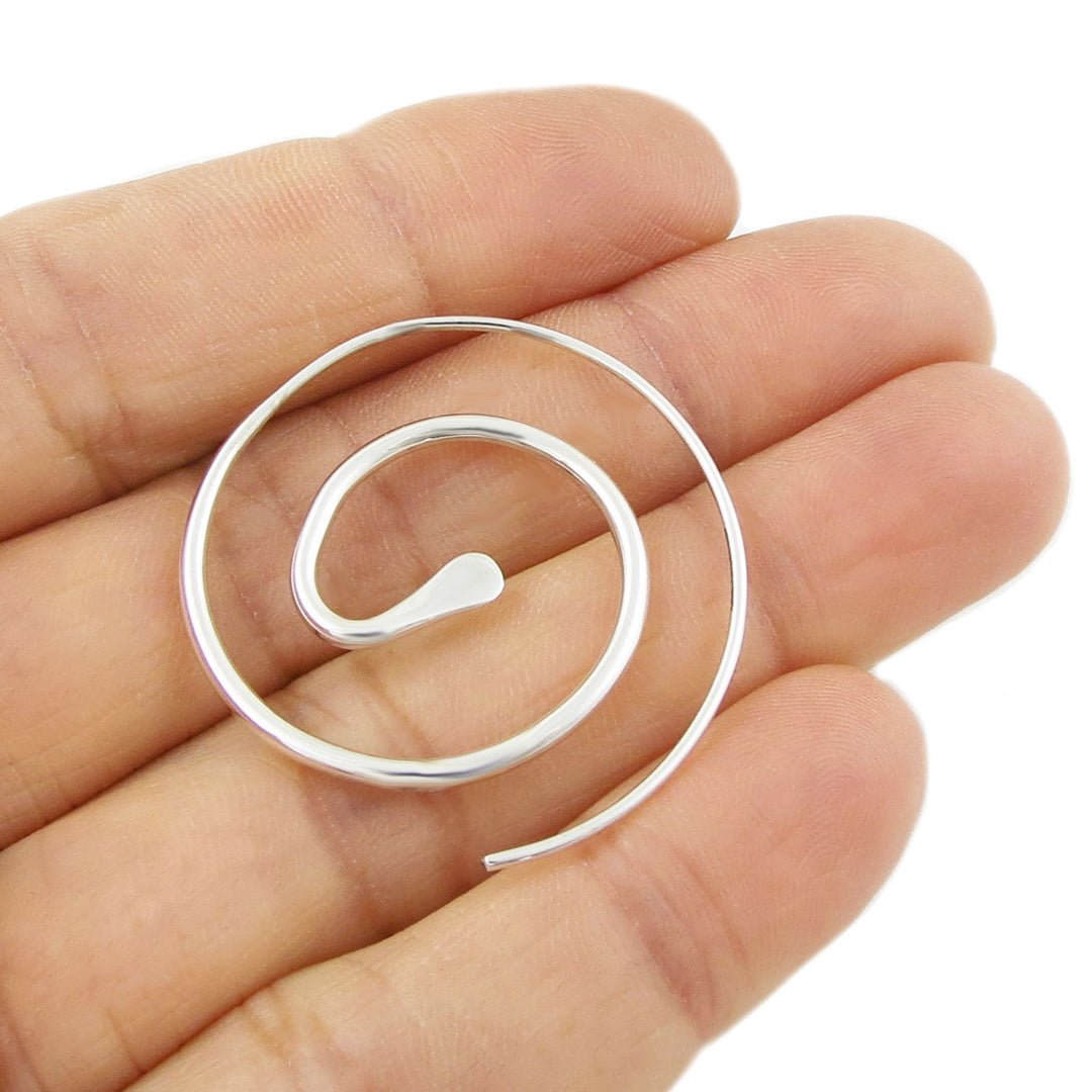 A large sterling 925 silver spiral earring for women held in a persons hand