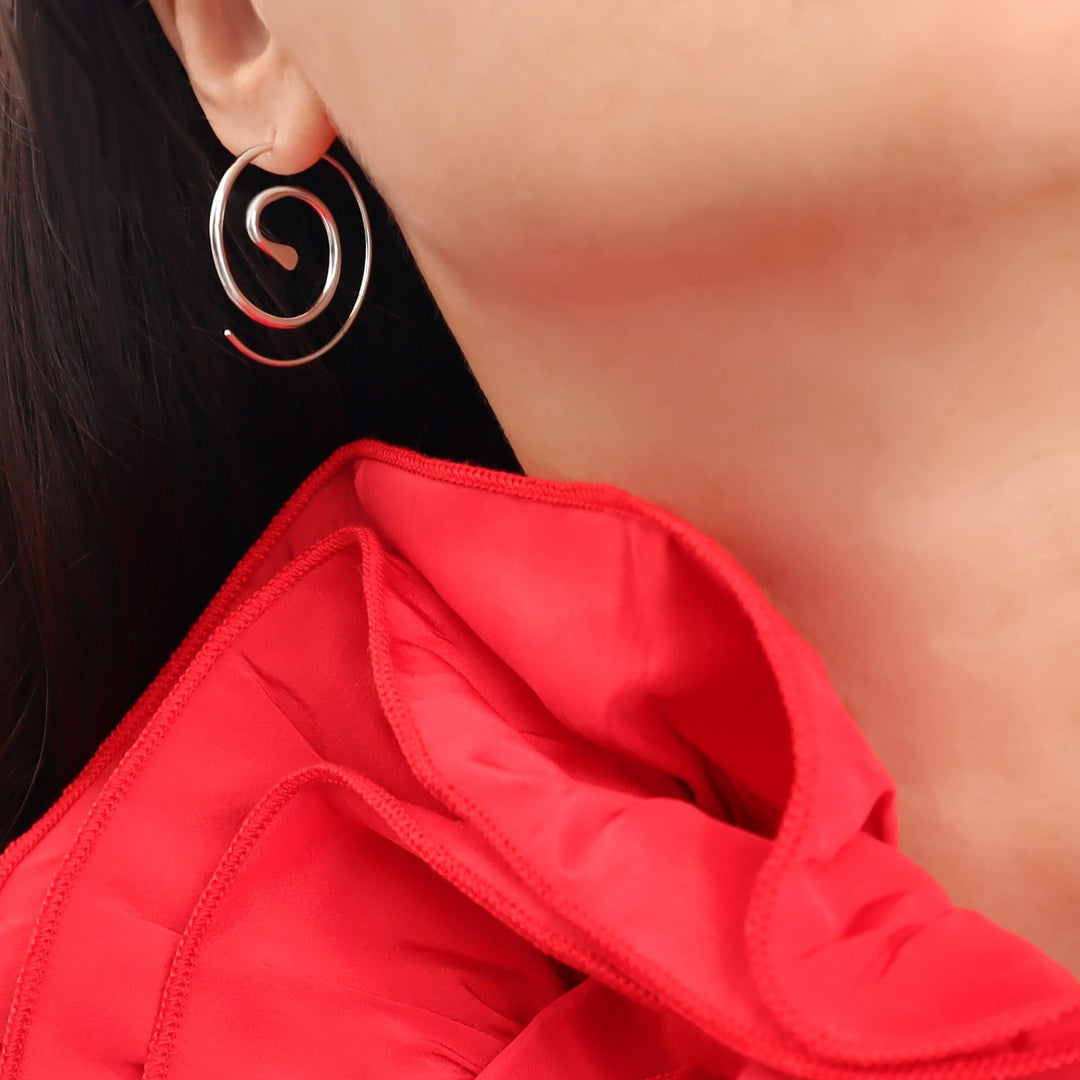Close-up of a woman wearing a red dress and solid 925 sterling silver handmade spiral hoop earrings.