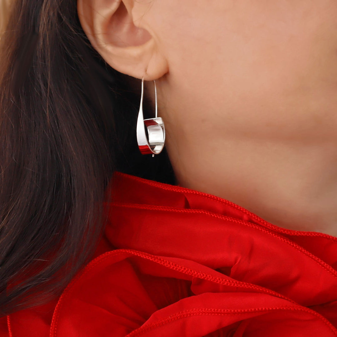 Close-up of a large 925 silver threader drop hoop style earring worn by a woman in a red dress
