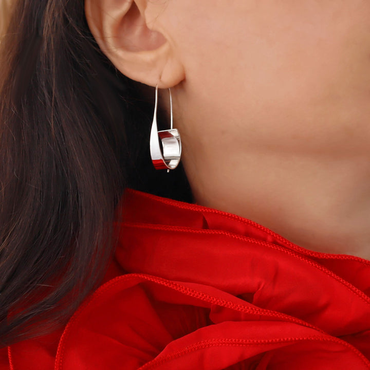 Close-up of a large 925 silver threader drop hoop style earring worn by a woman in a red dress