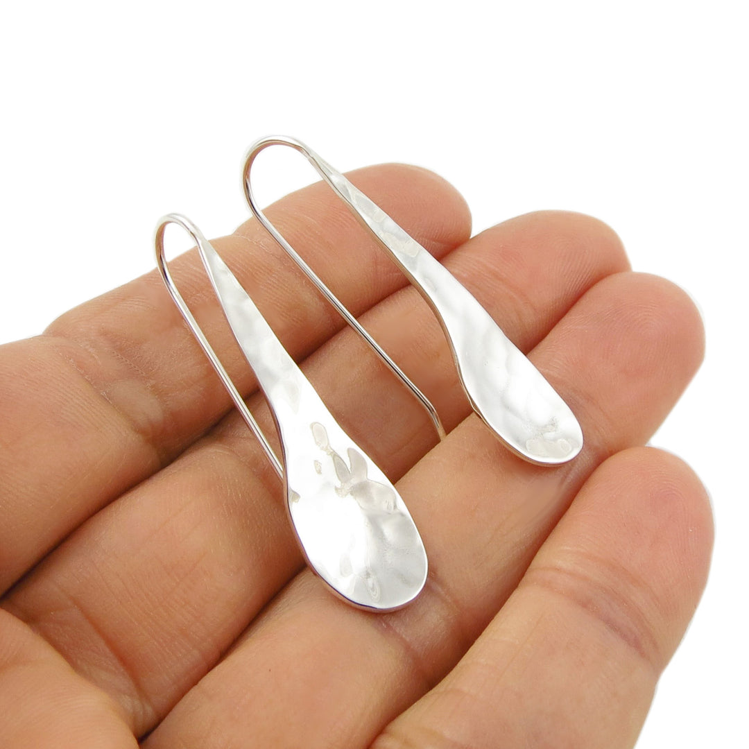 Sterling 925 Silver teardrop earrings held between fingers on a white background