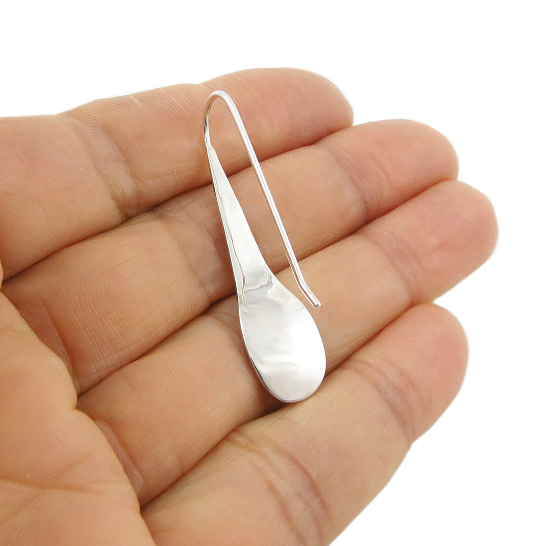 Silver earring with a long threader hook fastener held between fingers on a white background
