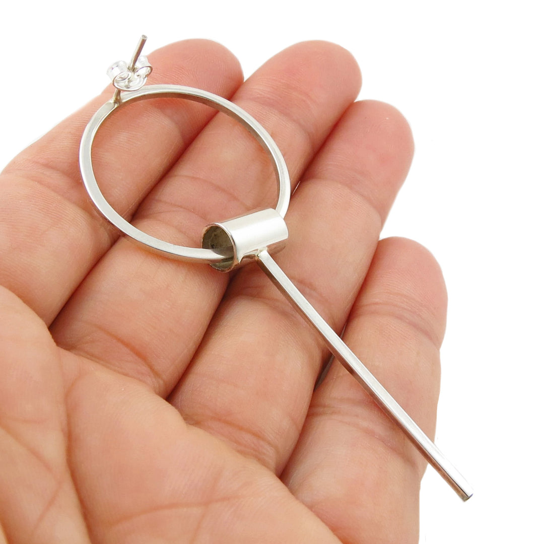 A large stick and drop statement earring for women in sterling 925 silver held in a person's hand to show the post and butterfly fastener. 