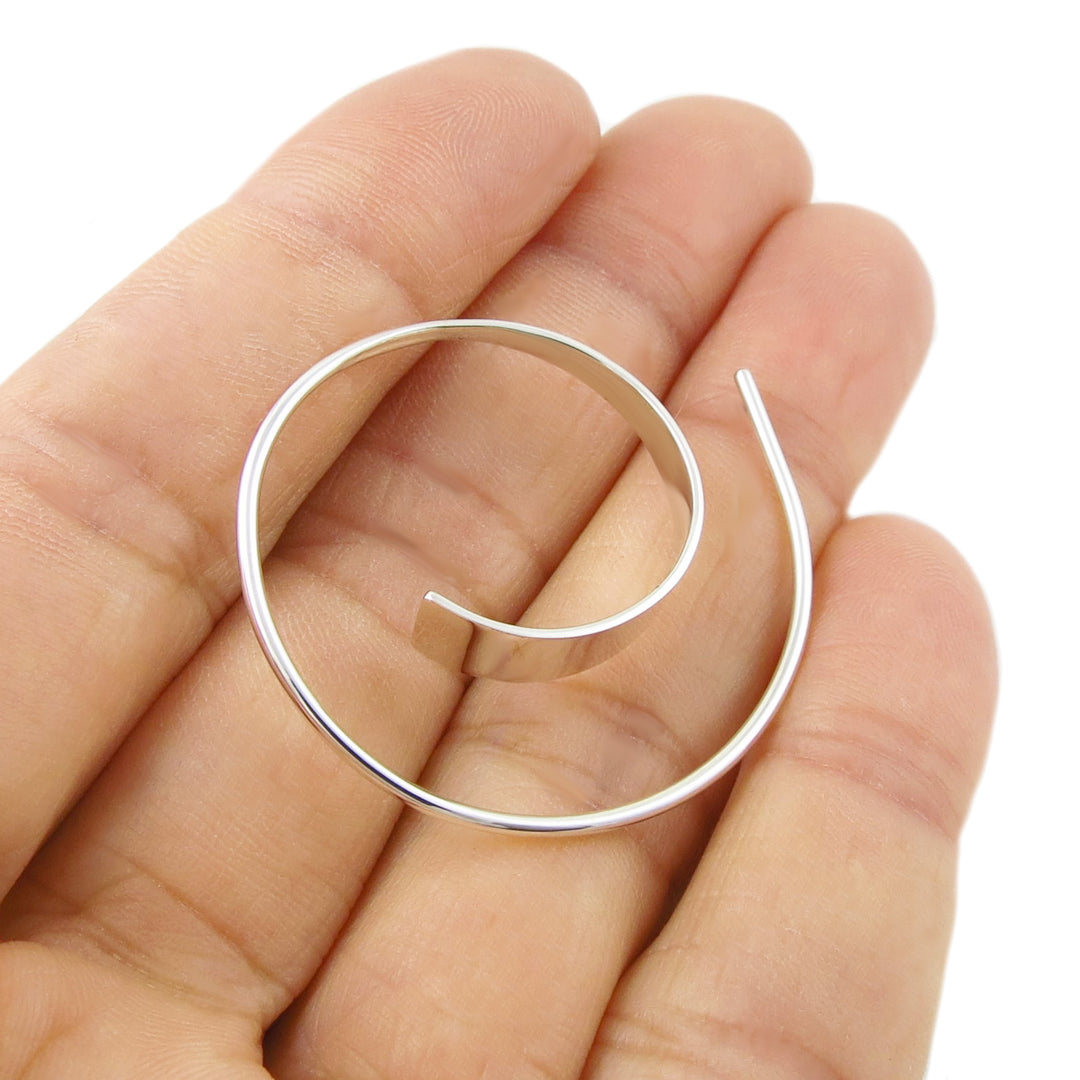 Womens handmade 925 silver hoop earring held between fingers against a white background