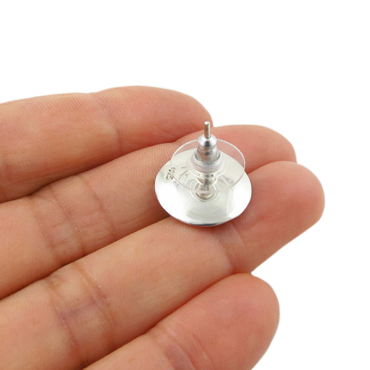 A small 925 silver stud earring with a clear round backing and a central metal post, shown resting on a person's fingers against a white background.