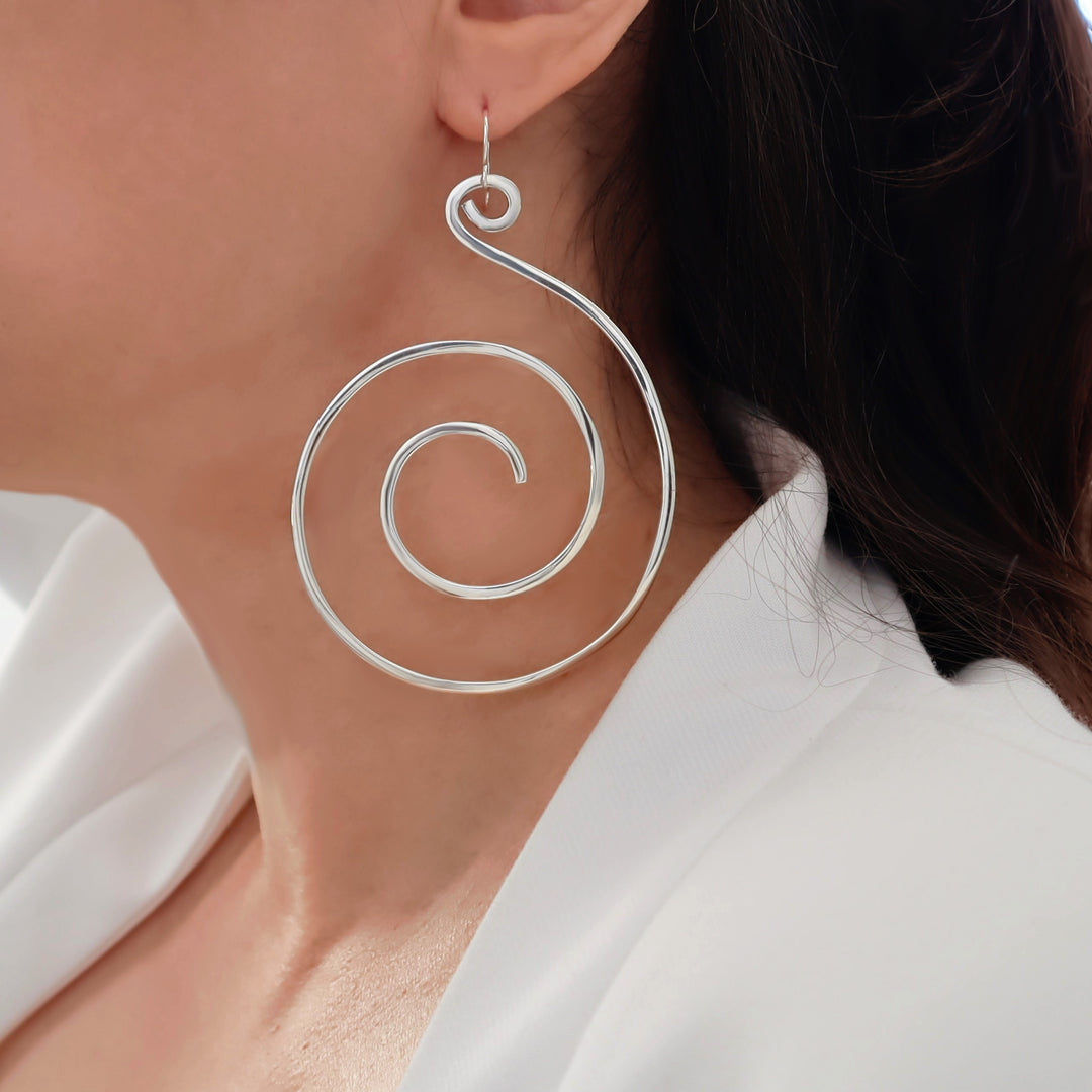 Extra large earrings featuring 925 sterling silver spirals worn by a woman with a white shirt