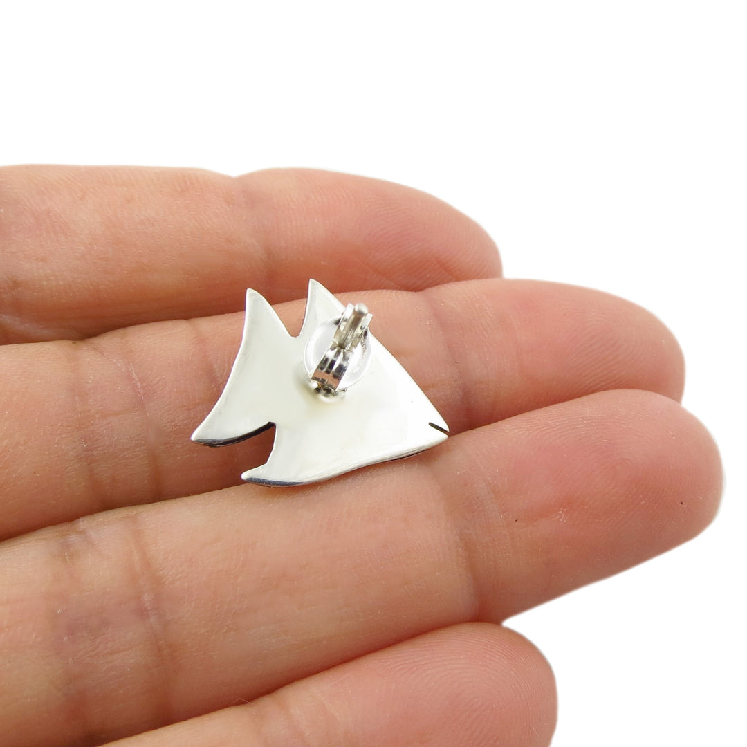 Reverse of a 925 silver fish shaped stud earring held in a woman's hand to show the 925 silver hallmark.  
