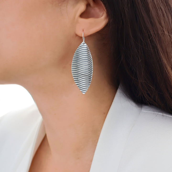 Long 925 silver leaf-shaped earring worn by a woman with a white background