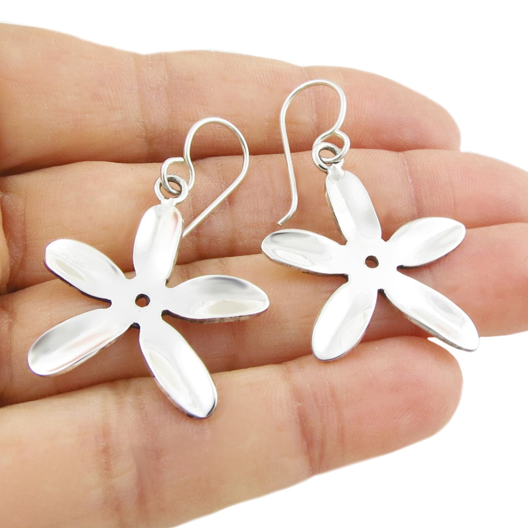 Solid 925 Silver daisy flower shaped earrings held in a hand against a white background