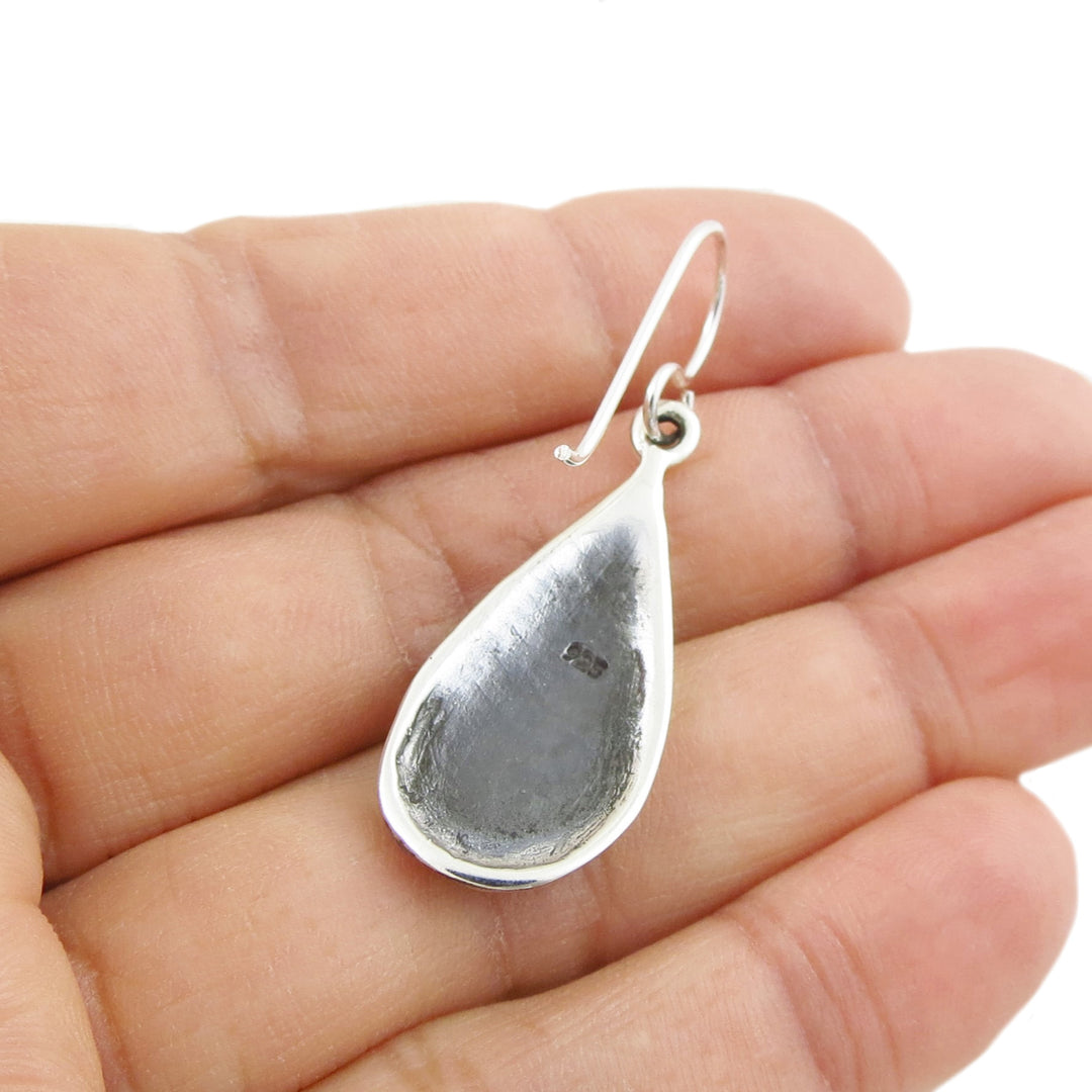 Solid 925 sterling silver handmade teardrop earring held upside down between fingers on a white background